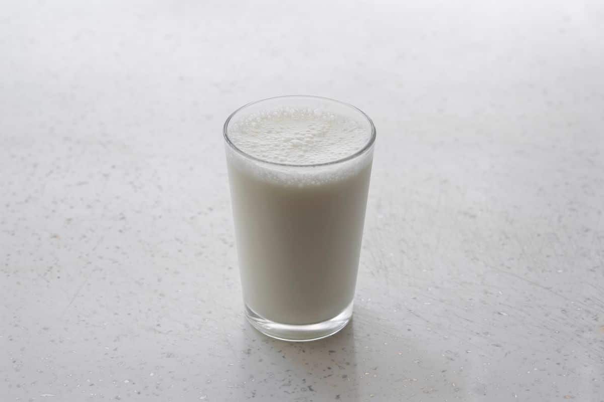 簡約背景下一杯乳白濃稠的甘酒，甘酒冷熱都適合飲用，冰鎮消暑或溫熱暖身都好喝