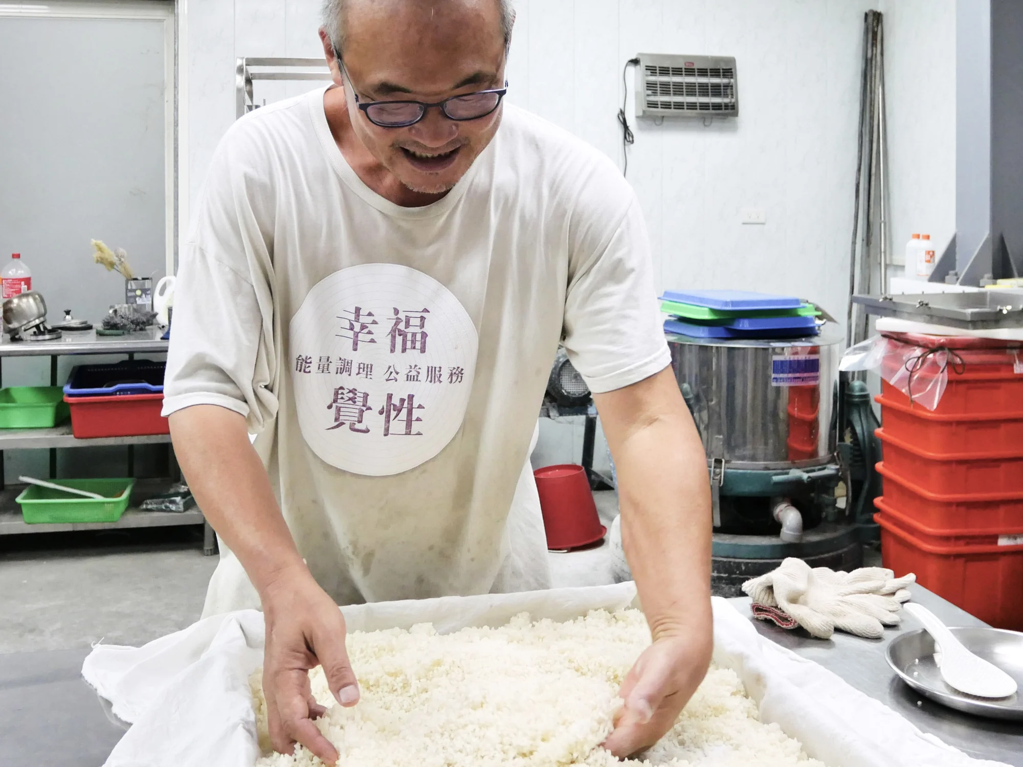 四季耕讀農園的慶豪在製麴室裡雙手翻拌蒸好的白米