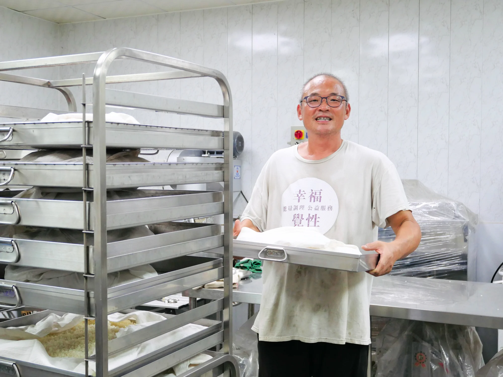 四季耕讀農園的慶豪在製麴室裡捧著一盤剛培養好的米麴