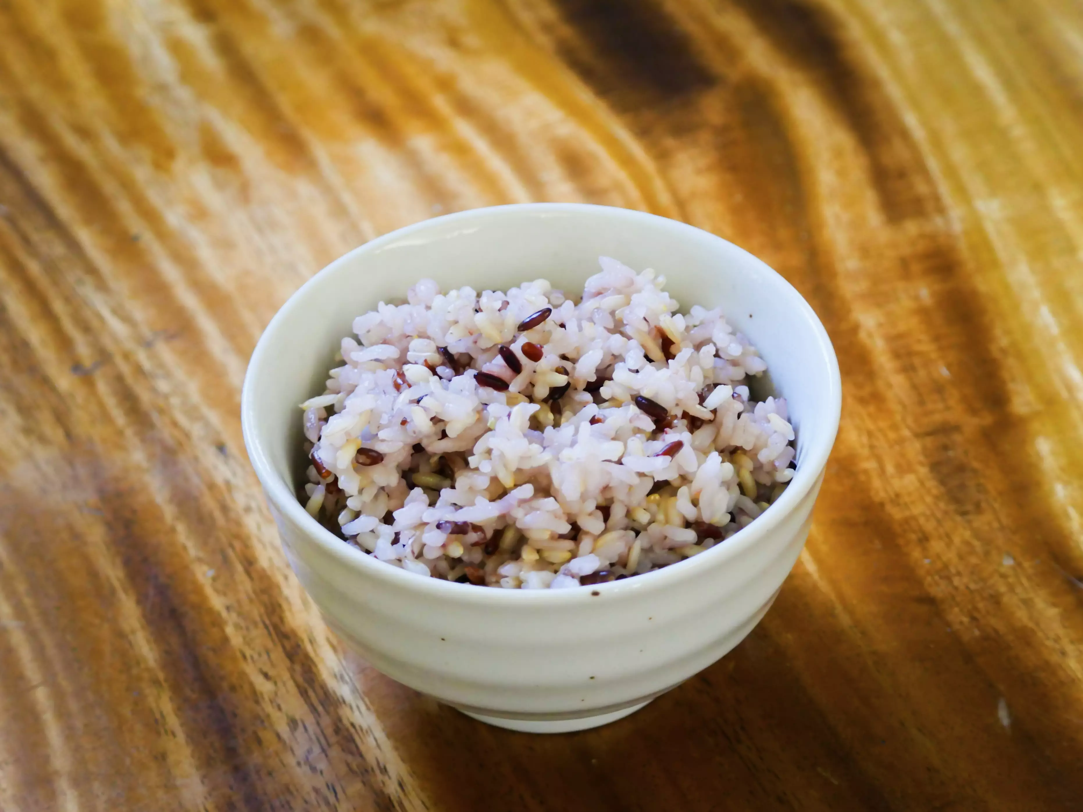 木紋桌上一小碗煮好的文晴米飯，看得到紫褐色米粒