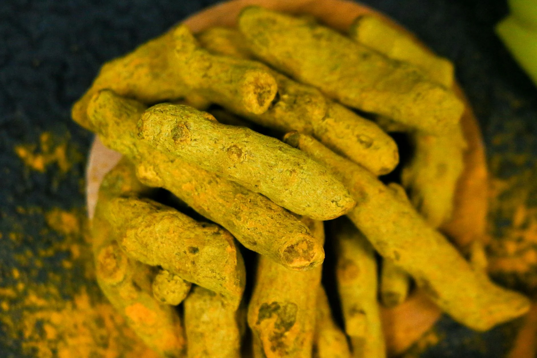 新鮮薑黃根莖置於木盤上特寫，薑黃是含薑黃素 curcumin 的根莖類香料植物
