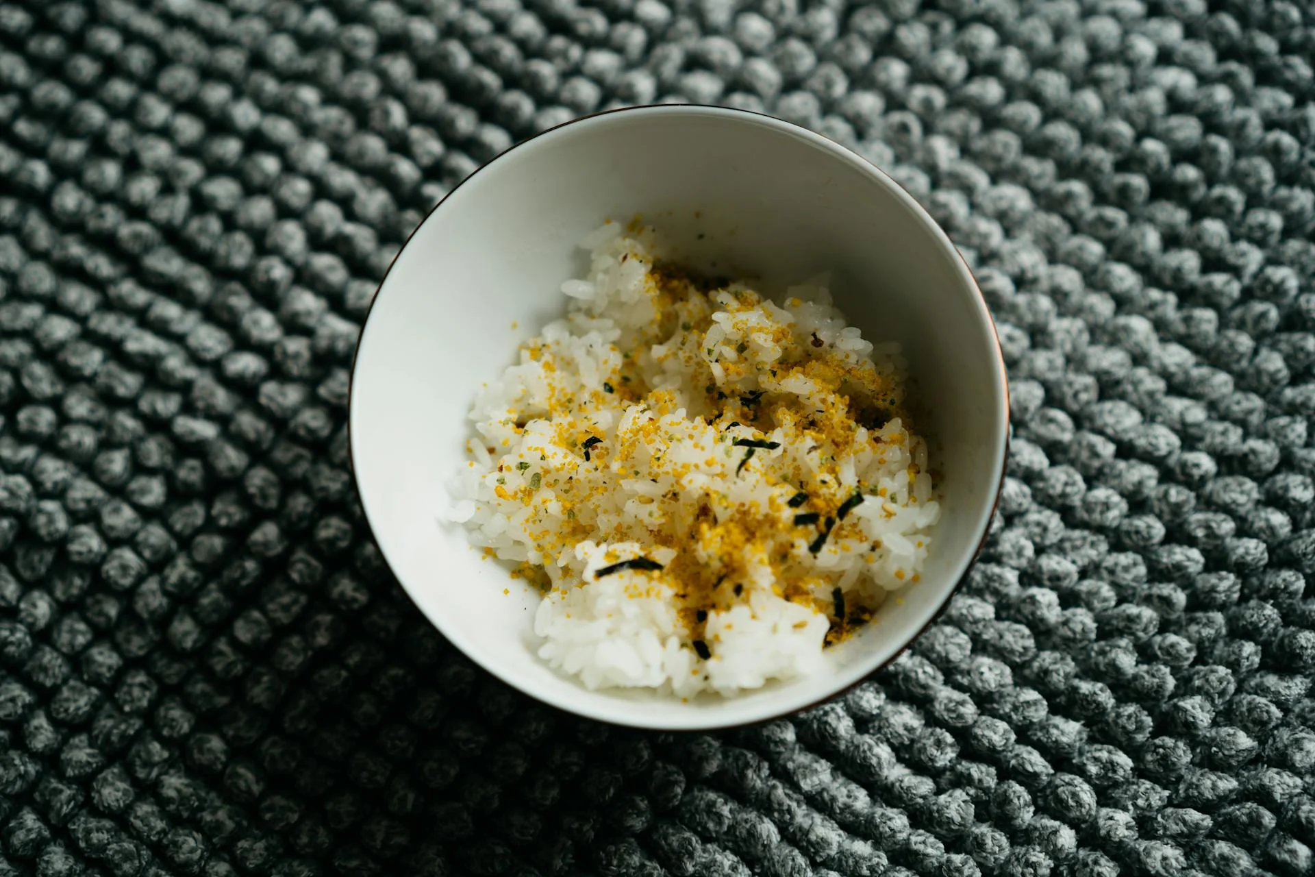 日式米飯碗裝上面撒了香鬆，是台中秈 10 號這類低 GI 米品種結為粒粒分明的烹煮表現許能照到