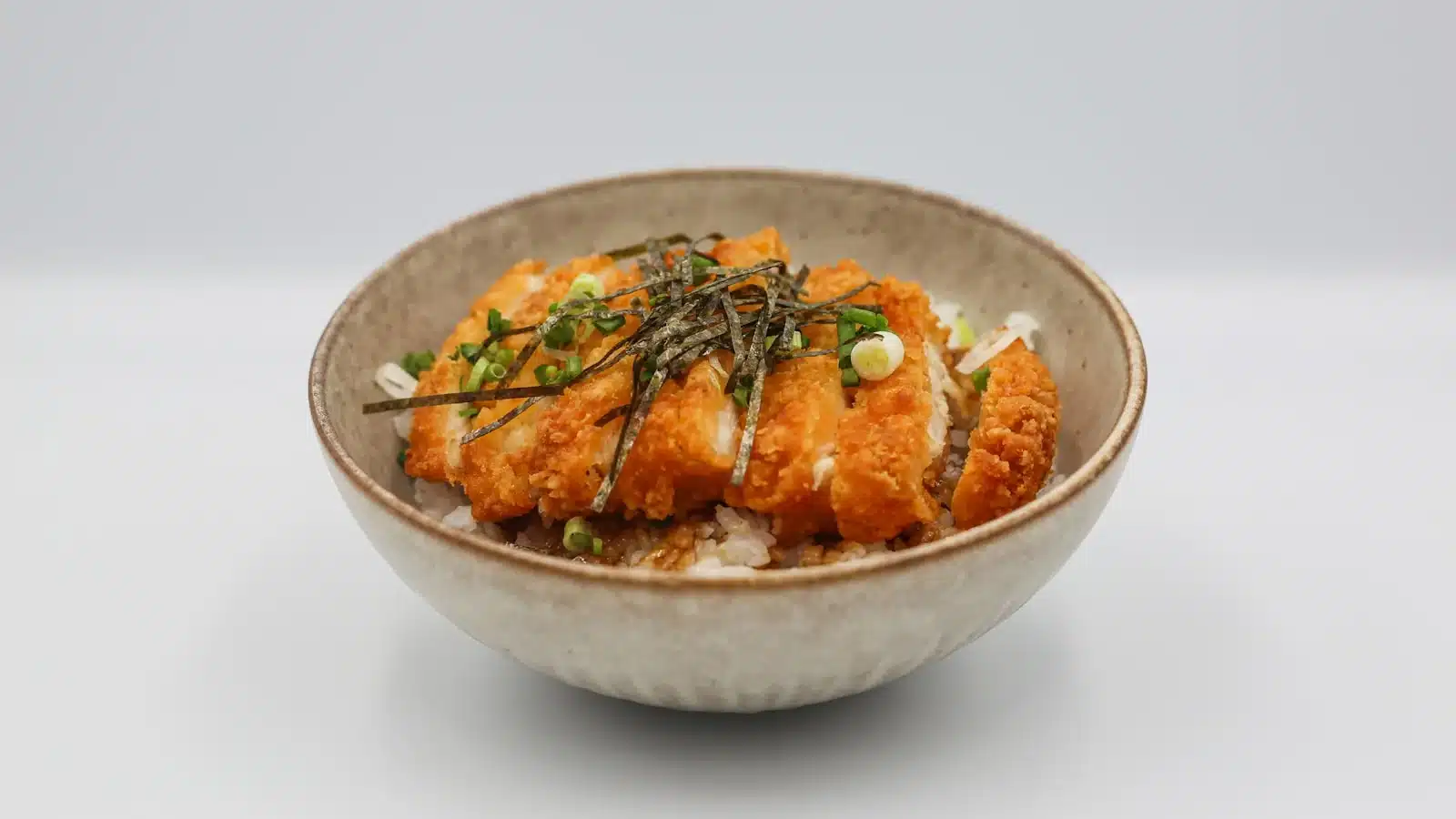 日式雞排丼成品近照,金黃酥脆的炸雞排切條鋪在白飯上,撒上海苔絲與青蔥