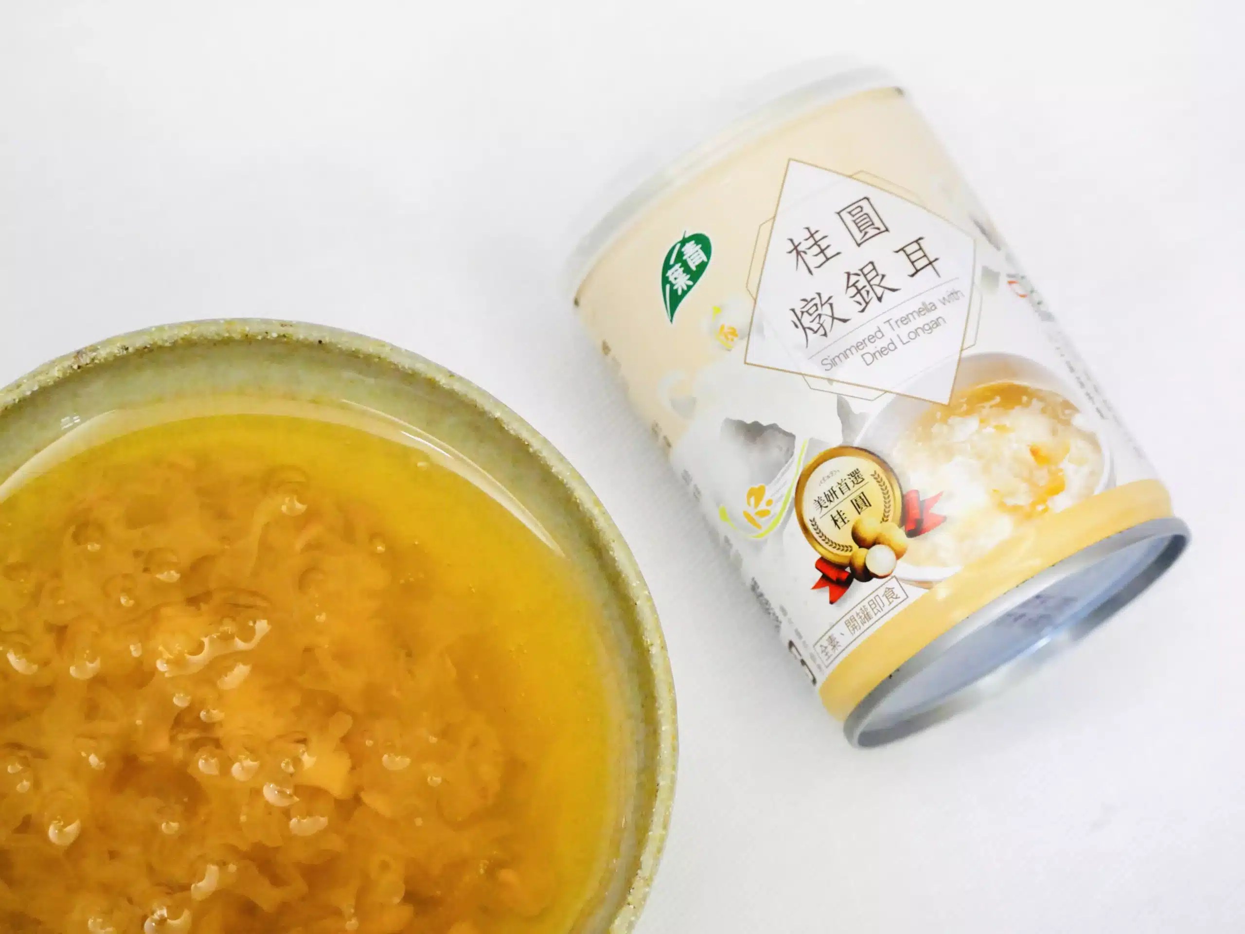 熬到出膠的銀耳湯特寫，湯汁濃稠掛勺、銀耳片透出膠感，旁邊放著桂圓燉銀耳罐裝