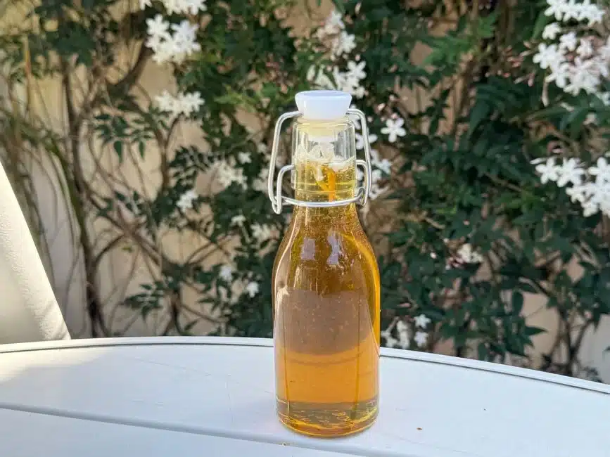 戶外桌面上一瓶玻璃瓶裝食用油與白色小花，呈現好油應避光陰涼保存的原則