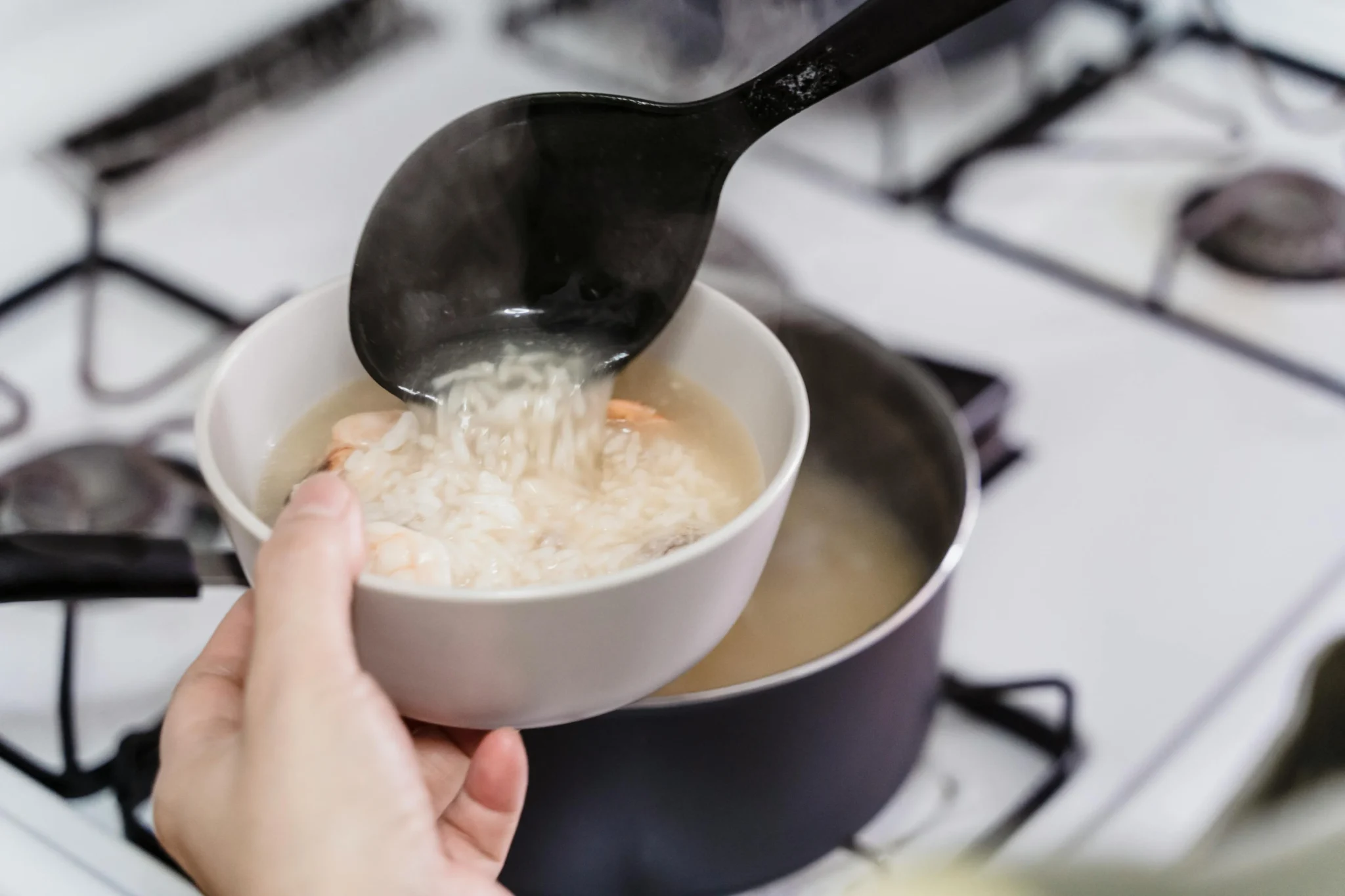 煮紫米飯時鍋蓋掀開冒出蒸氣，紫米飯帶花青素染色完整