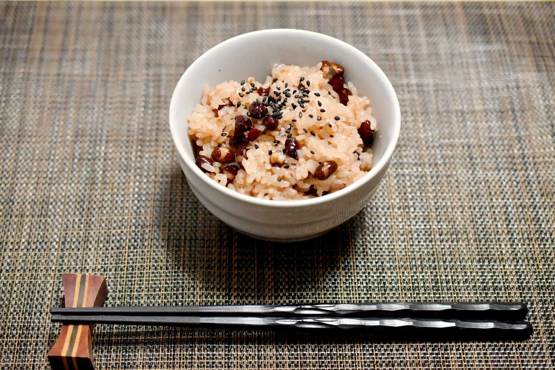 陶碗裡拌了黑芝麻的胚芽米飯，旁邊擺著一雙木筷，飯粒帶著淡黃色的胚芽
