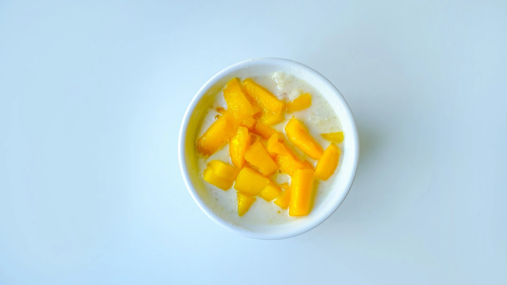 白瓷碗裝切丁芒果料理放在淺色桌上的切後保存場景