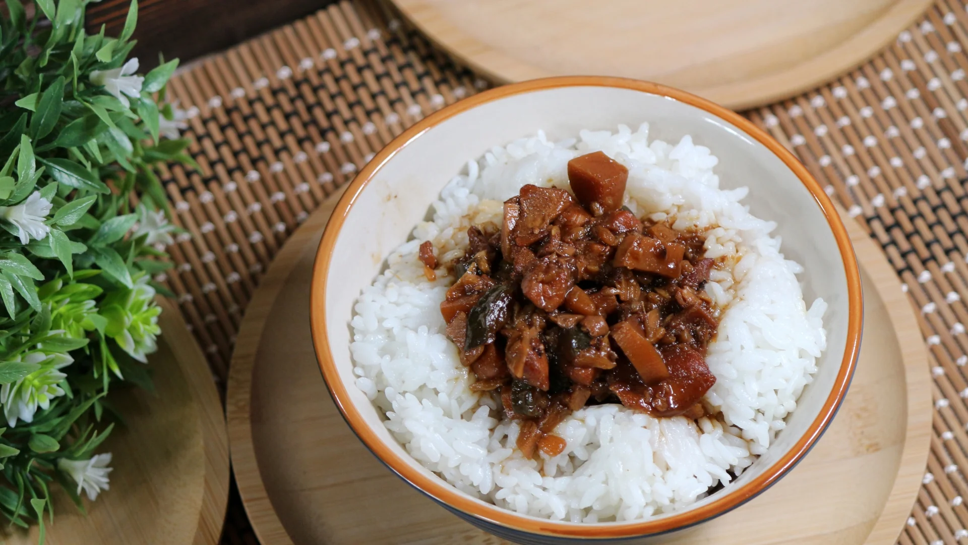 竹編桌墊上的一碗滷肉飯，白飯中央舀上滷得油亮的肉燥