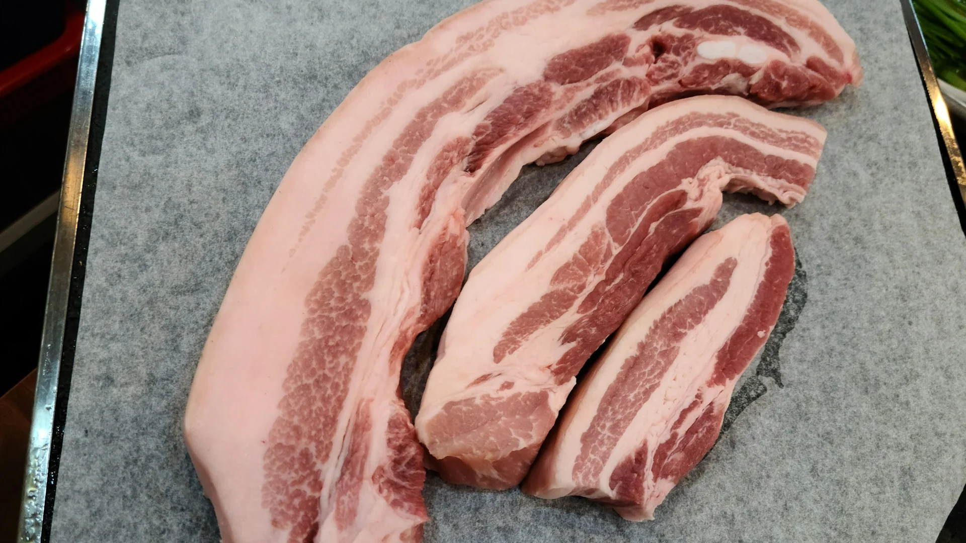 砧板上的生五花肉塊，三層分明的油花是滷肉不乾的本錢