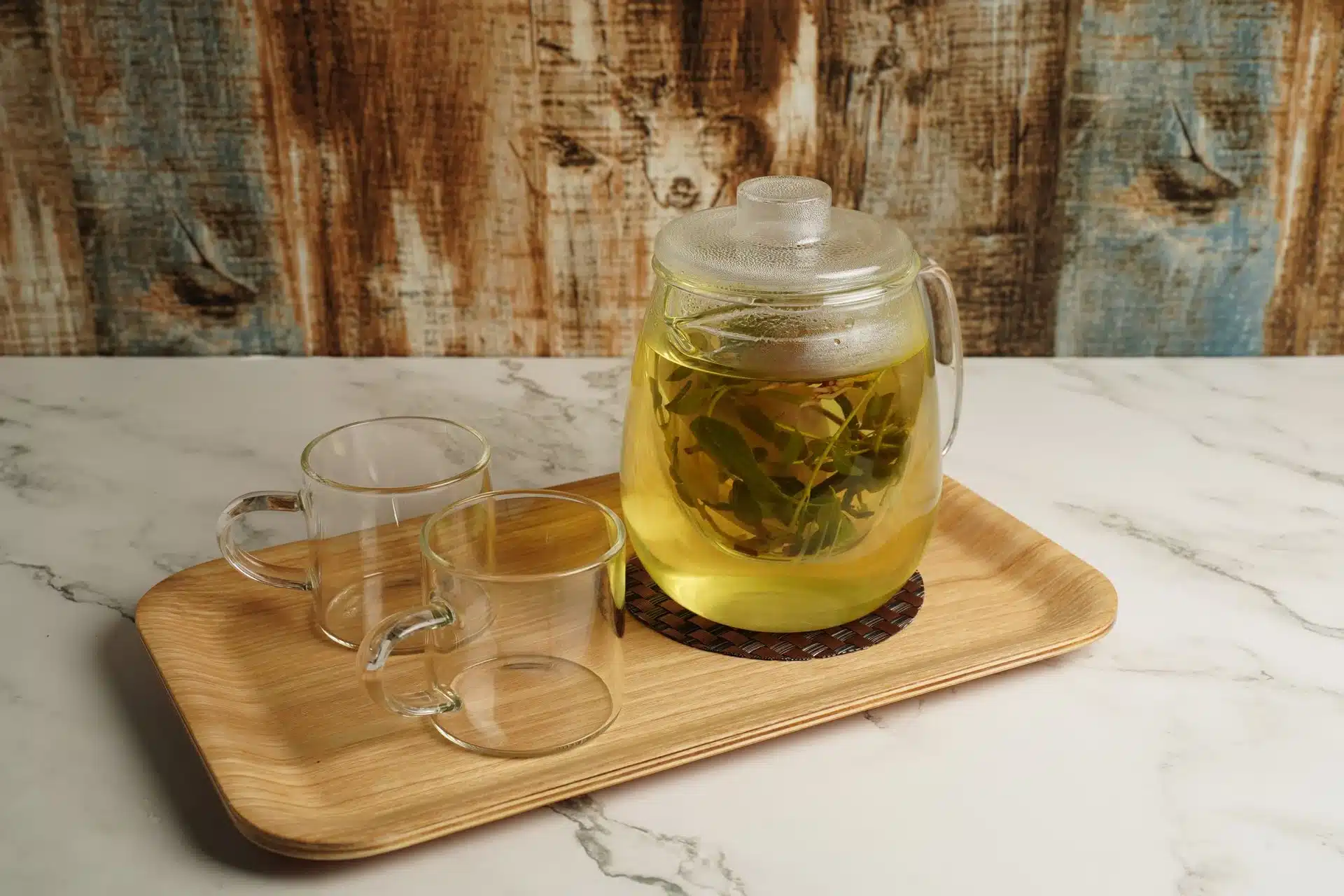 玻璃茶壺裡金黃色的玄米茶茶湯，搭配兩個玻璃杯擺在木托盤上