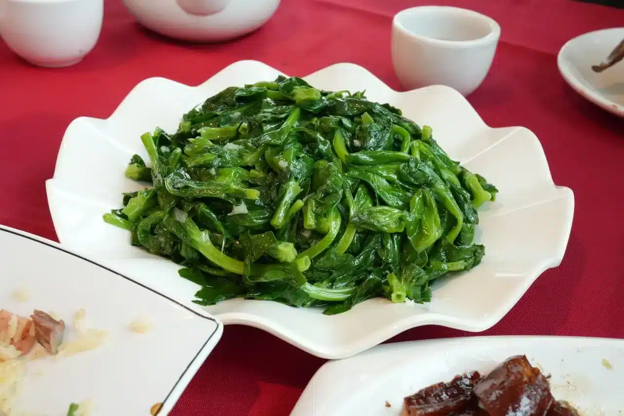 白盤裝著炒綠葉菜，綠葉菜硝酸鹽含量高，建議當餐吃完