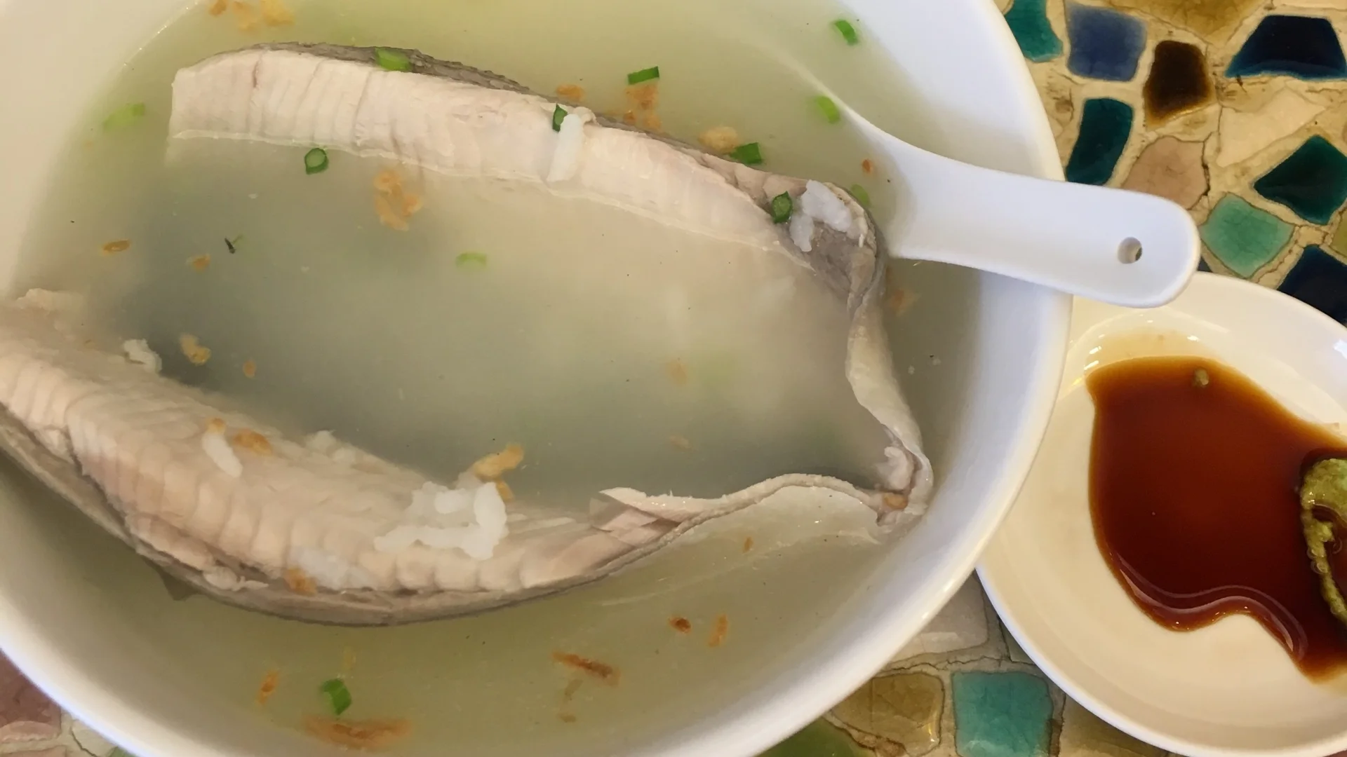 白碗裡的虱目魚肚湯，上面撒了油蔥酥與蔥花