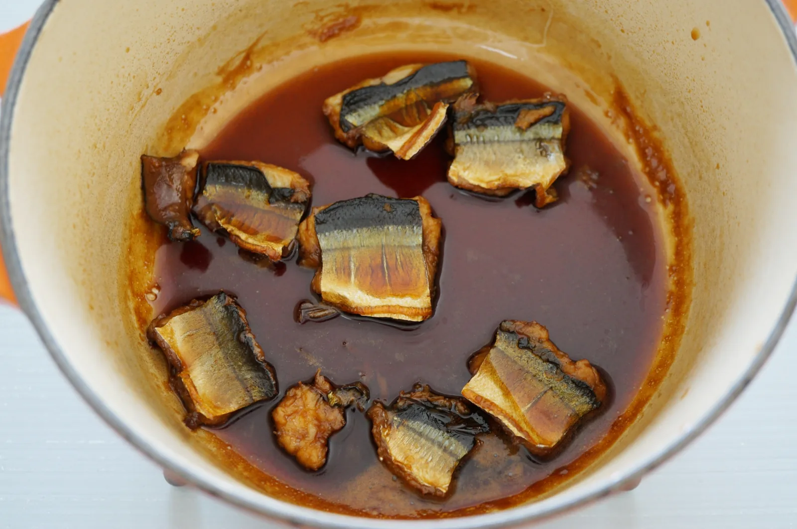 鍋中的秋刀魚甘露煮，切段的秋刀魚在醬油醬汁中慢燉入味，連骨都能吃