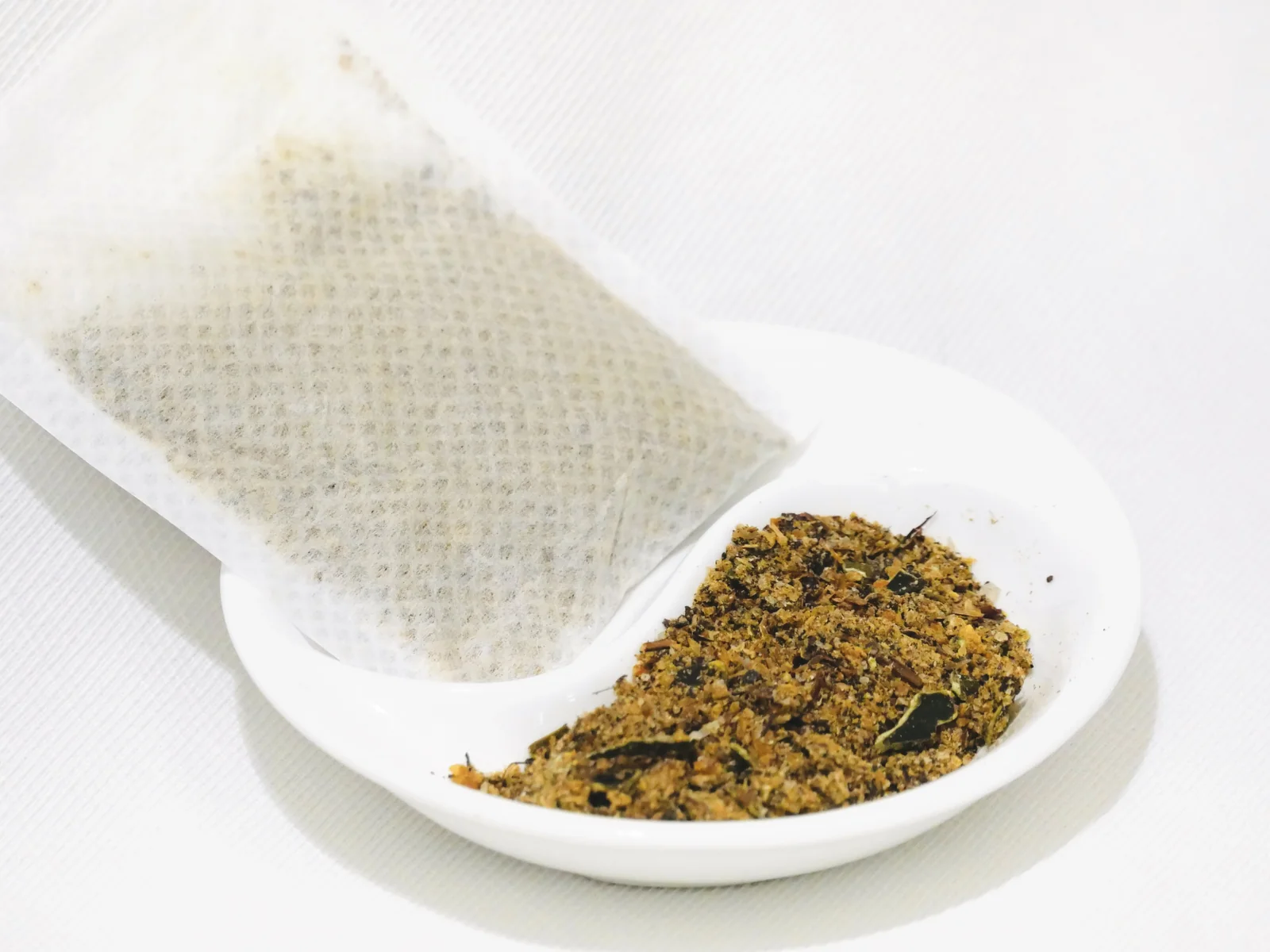 高湯包特寫,旁邊白碟裡是凍乾磨碎的高湯食材