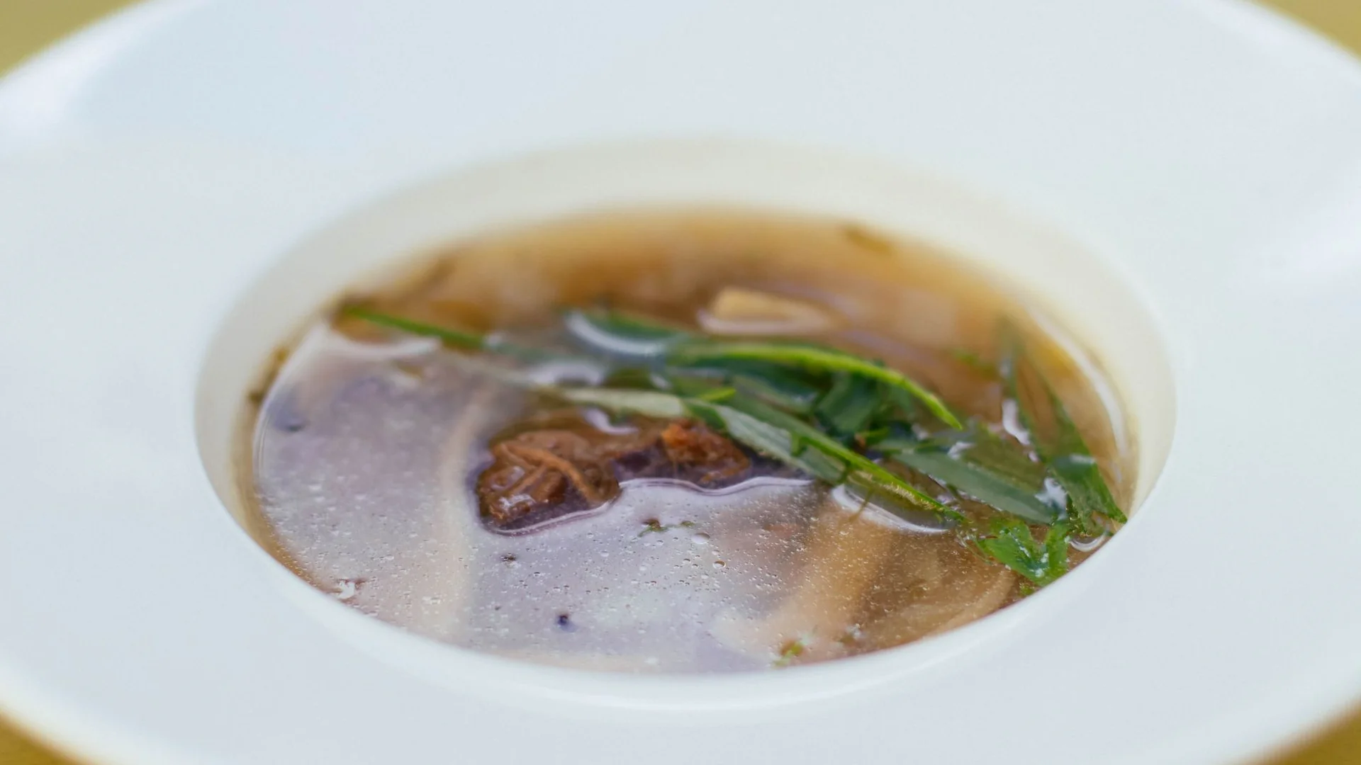 白瓷盤盛裝的清澈排骨湯，湯裡有肉塊與青蔬，示範山藥排骨湯煮好不混濁的樣子