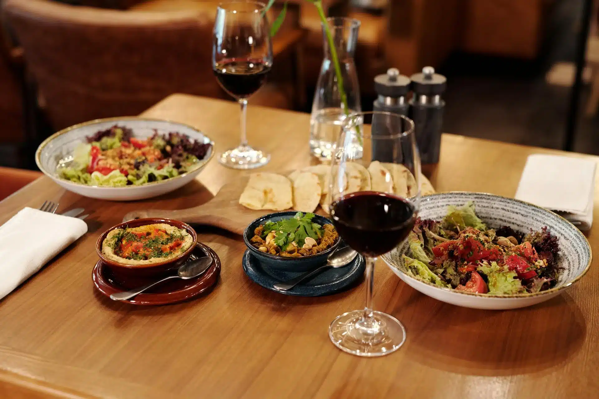 地中海飲食佈滿桌面，含橄欖、起司、蔬菜、麵包與醀酒杯等多元食材，代表地中海飲食的完整餐餓
