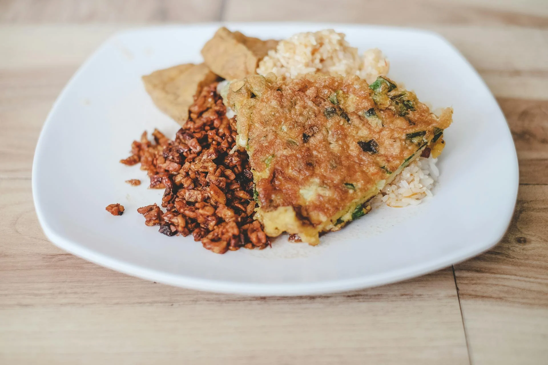 印尼餐盤上有煎天貝切片、米飯與炸物配菜俯拍，呈現天貝在原產地的代表料理場景