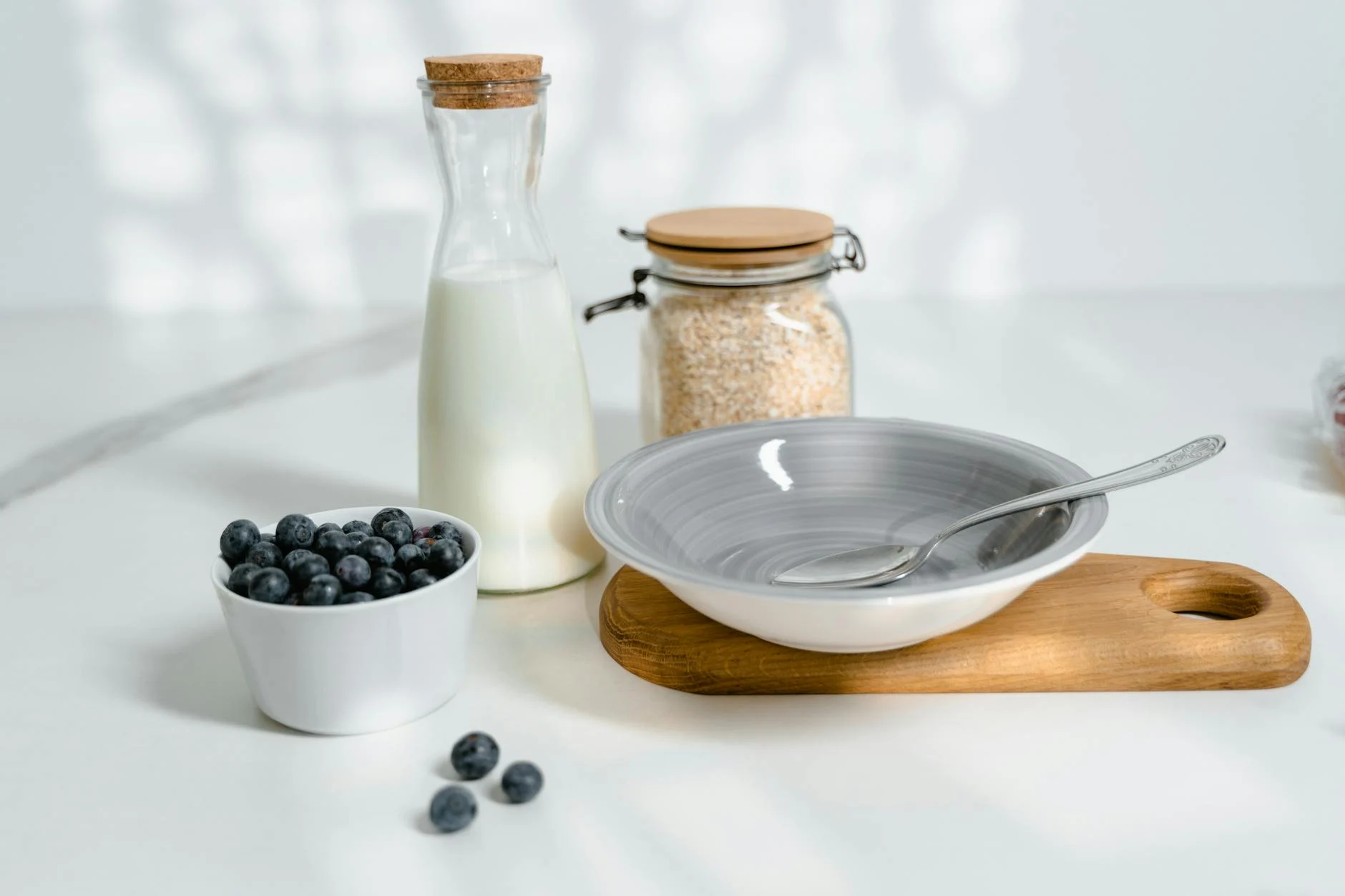 Rolled oats in a glass jar with blueberries and bread, cool-toned breakfast flat lay - yilanmart oat cooking article featured image
