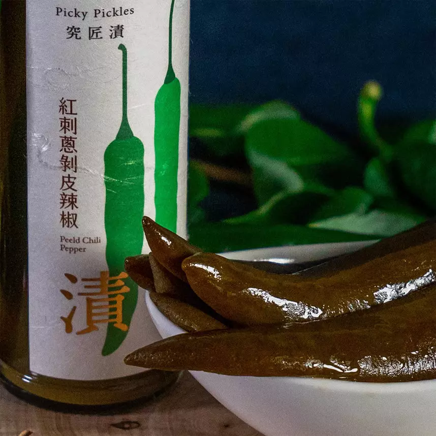 究匠漬茶油剝皮辣椒的玻璃瓶身,標籤印著兩條青辣椒